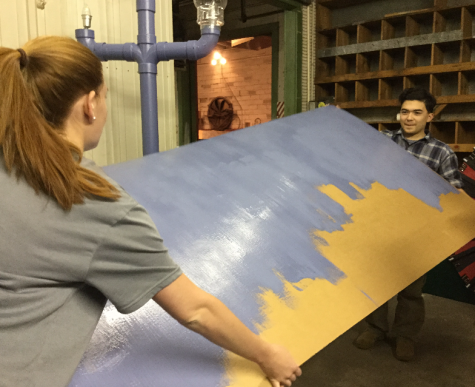 Anna Young and Jimmy Fortner flip over a prop to paint. 