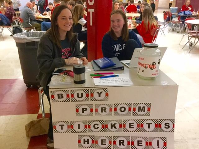 Juniors Kelsey Wilson and Adison Wash watch over the prom ticket table, which has the donation canister for the open-lunch fundraiser.
