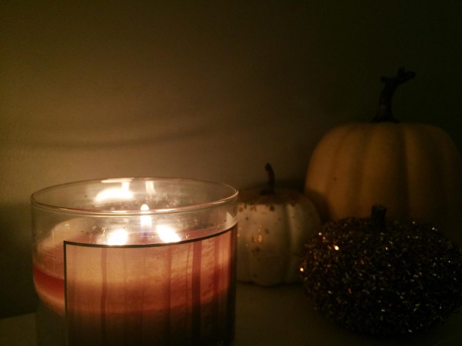Candle with pumpkins in the background