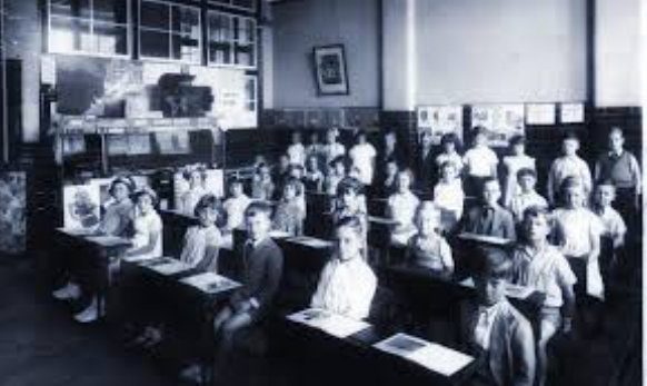 A class room full of kids learning, in the 1900s.